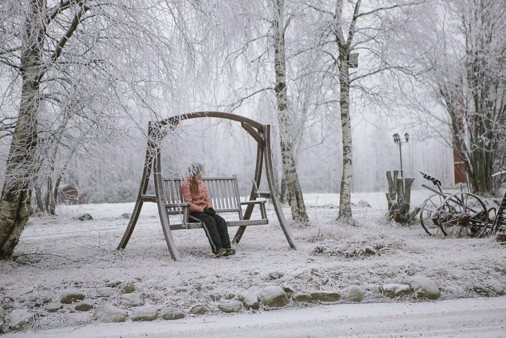 Henkilö istahtanut keinuun lumisessa Ronivaarassa