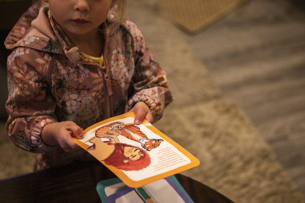 Lapsi pitää kuvakorttia käsissään muiden korttien ollessa pöydällä.